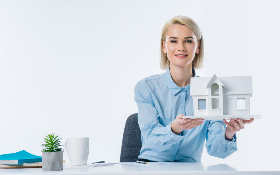 portrait of real estate agent showing house model at workplace